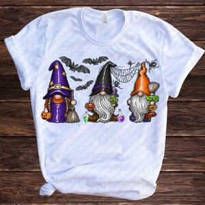 May include: Three gnomes dressed in Halloween costumes. The gnome on the left is wearing a purple and black witch hat and holding a broom. The gnome in the middle is wearing a black hat and holding a pumpkin. The gnome on the right is wearing an orange hat and holding a sign that says "Trick or Treat".