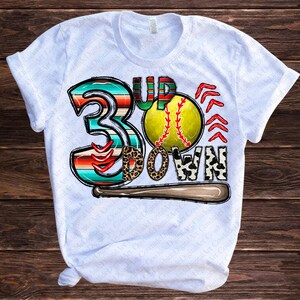 Puede incluir: Camiseta blanca con un dise&ntilde;o gr&aacute;fico colorido que presenta una pelota de b&eacute;isbol, un n&uacute;mero 3 y las palabras "3 Up Down".