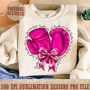 May include: Pink boxing gloves with a sparkly pink bow on a white sweatshirt. The text "We Fight Together We Win Together We Fight Together We Win Together We Fight Together We Win" is written around the gloves.