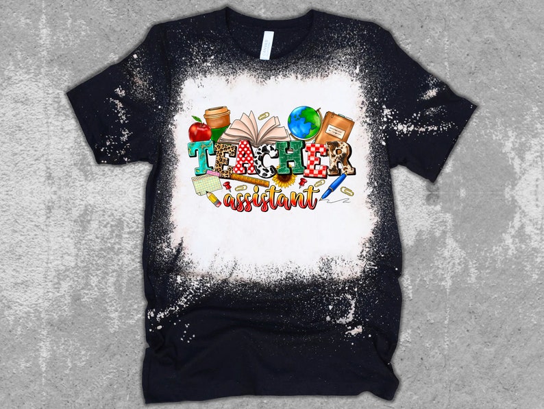 K&ouml;nnte beinhalten: Ein schwarzes T-Shirt mit einem Bleiche-Spritzer-Design mit dem Text "Teacher assistant" umgeben von bunten Schulutensilien und einem Globus.