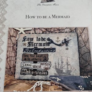 May include: A cross-stitch pattern with the text "How to be a Mermaid" and a list of instructions: "Be Enchanting", "Sea the best in others", "Sing your song", "Make waves".