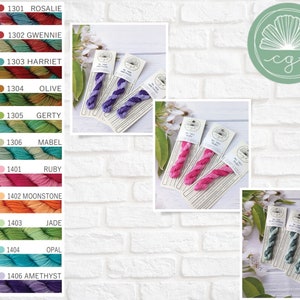 May include: A color chart of embroidery floss with 10 different colors. The colors are: Rosalie, Gwenie, Harriet, Olive, Gerty, Mabel, Ruby, Moonstone, Jade, Opal, and Amethyst. The floss is wound on cards with the color number and name printed on each card.