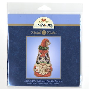 May include: A cross-stitch pattern featuring a gnome holding a glass of milk and a cookie. The pattern is titled "Milk and Cookie Gnome" and is by Jim Shore, Mile Hill. The design size is 2.5 inches wide by 5 inches high, or 6.4 cm by 12.7 cm.
