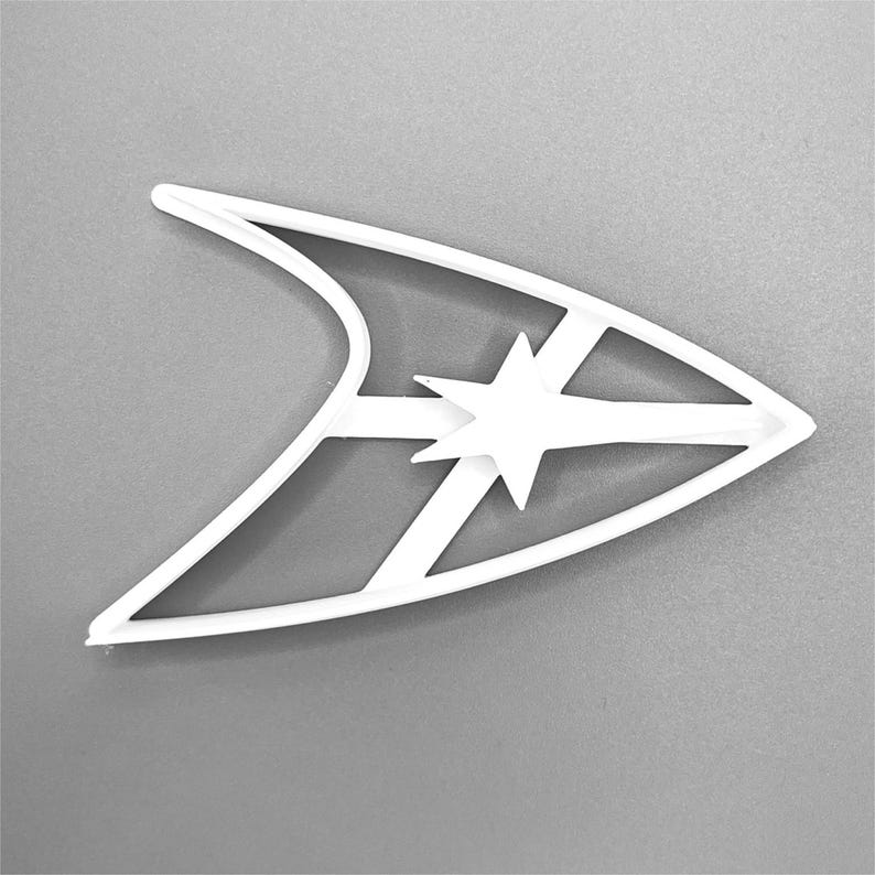 Puede incluir: Cortador de galletas de pl&aacute;stico blanco con forma del emblema de Star Trek, con una estrella estilizada en el centro.