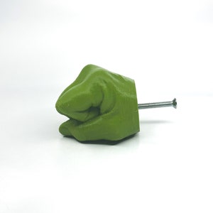 May include: A green 3D printed hand shaped like a fist with a silver screw protruding from the back.