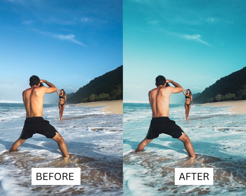May include: A person taking a photo of another person standing in the ocean on a sandy beach. The person taking the photo is wearing black shorts and the person being photographed is wearing a black bikini.