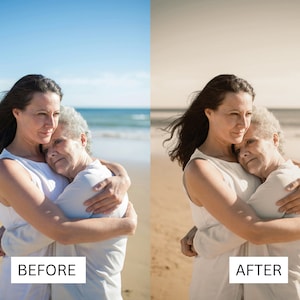 May include: Two women, one older and one younger, are hugging on a beach. The younger woman has long dark hair and is wearing a white tank top. The older woman has short gray hair and is also wearing a white tank top. The women are standing on a sandy beach with the ocean in the background.