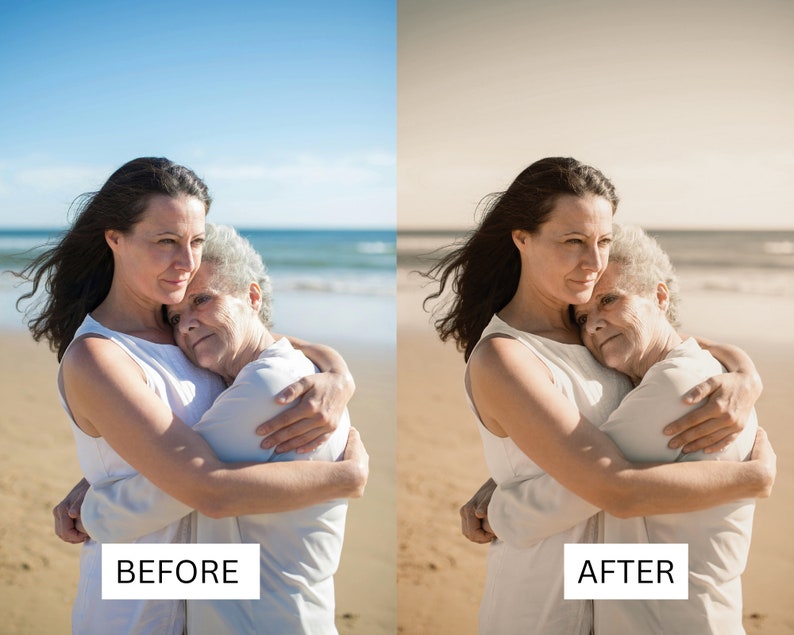 May include: Two women, one older and one younger, are hugging on a beach. The younger woman has long dark hair and is wearing a white tank top. The older woman has short gray hair and is also wearing a white tank top. The women are standing on a sandy beach with the ocean in the background.
