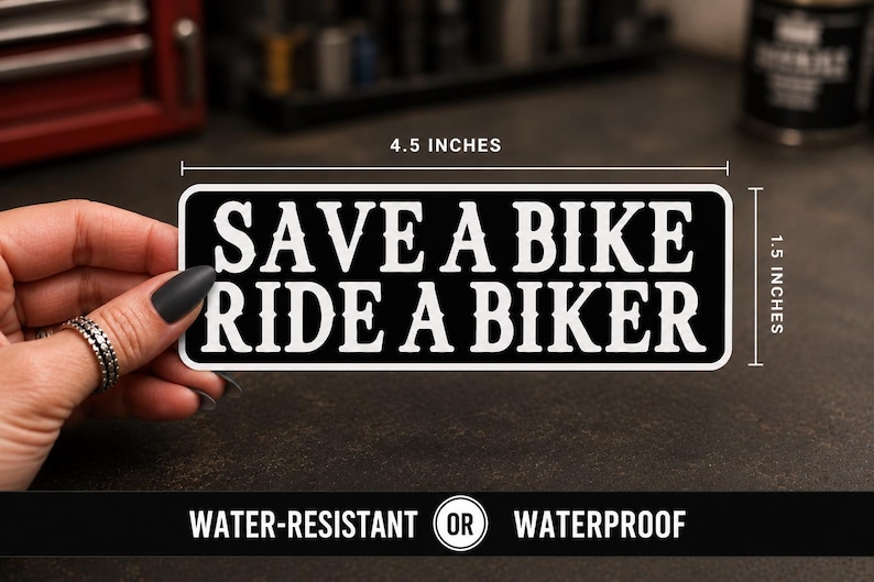 May include: A rectangular black sticker with white text that reads SAVE A BIKE RIDE A BIKER. The sticker features a white border and measures 4.5 inches in width by 1.5 inches in height as indicated by the visible measurement lines in the image.