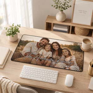 Könnte beinhalten: Eine rechteckige Schreibtischunterlage mit einem aufgedruckten Foto einer vierköpfigen Familie, die auf einem Feld sitzt. Das Bild zeigt einen Mann, eine Frau und zwei lächelnde Kinder mit dem weißen Schreibschrifttext "The Anderson Family".