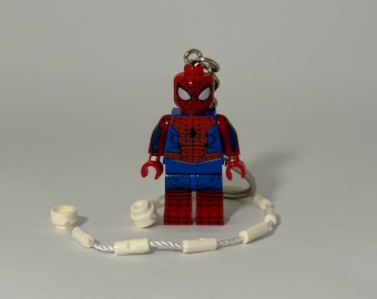 May include: A red and blue Lego minifigure of Spider-Man with a white web keychain attached.