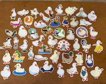 Puede incluir: Una colección de pegatinas de patos coloridos en varias poses y estilos. Algunos patos usan sombreros, montan en patineta o usan trajes espaciales. Las pegatinas están sobre una superficie marrón.