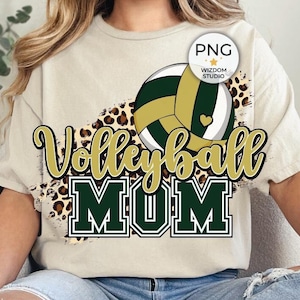 May include: A woman wearing a beige t-shirt with a green and gold volleyball graphic and the text "Volleyball Mom" in gold letters. The graphic includes a leopard print pattern.