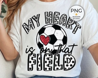 May include: White t-shirt with a black and white soccer ball graphic and the text "My heart is on that field".