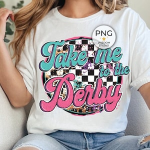 May include: A white t-shirt with a pink, blue and black graphic design that says "Take me to the Derby".