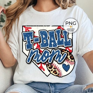 Peut inclure: T-shirt blanc avec un graphique de diamant de baseball bleu et rouge qui dit "T-Ball Mom" avec un ballon de baseball bleu scintillant et des accents léopard.