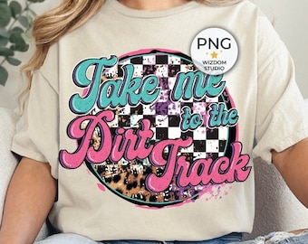 May include: A white t-shirt with a pink, blue, and black graphic design that says "Take me to the Dirt Track". The graphic design features a checkered flag, leopard print, and splattered paint.