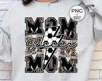 May include: Gray sweatshirt with a black and white graphic design featuring the words "MOM Soccer MOM" with a soccer ball and lightning bolt. The graphic is surrounded by a leopard print pattern.