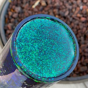 Pu&ograve; includere: Primo piano di un bicchiere di glitter nero e verde. Il bicchiere ha una finitura liscia e lucida ed &egrave; ricoperto da uno strato di glitter fine.