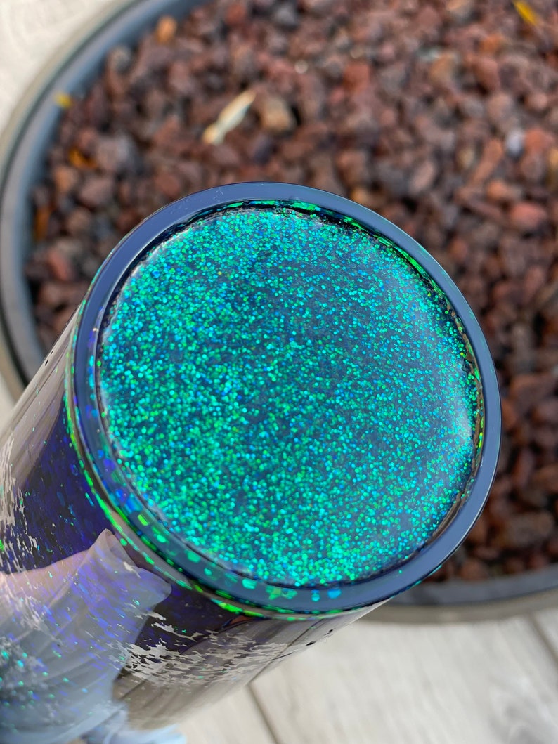 Pu&ograve; includere: Primo piano di un bicchiere di glitter nero e verde. Il bicchiere ha una finitura liscia e lucida ed &egrave; ricoperto da uno strato di glitter fine.