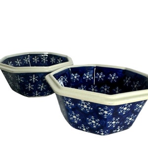 May include: Two blue and white ceramic bowls with a snowflake pattern. The bowls are octagonal in shape and have a white rim.