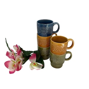 May include: Set of four vintage ceramic mugs with a stacked design. The mugs are in shades of blue, green, and brown with a repeating pattern.