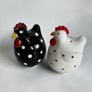 May include: A white ceramic mug with a black handle and the text "But First, Coffee" in a bold, black font. The mug is set against a blurred background, suggesting a cozy setting.