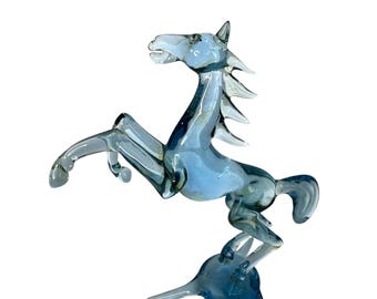 May include: A blue glass horse figurine with a spiky mane and tail, standing on a three-pronged base.