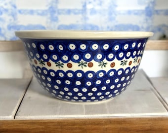 Puede incluir: Un tazón mezclador de cerámica azul y blanco con un patrón floral marrón y verde alrededor del borde. El tazón tiene un interior blanco y está decorado con un patrón de lunares.