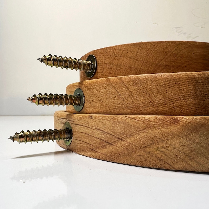 May include: Three wooden hoops with brass screws, stacked on top of each other. The hoops are unfinished and have a natural wood grain.