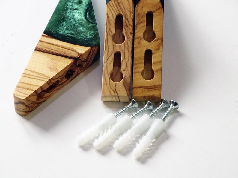May include: Two wooden wall mounts with green epoxy resin inserts and four white plastic drywall anchors and screws.