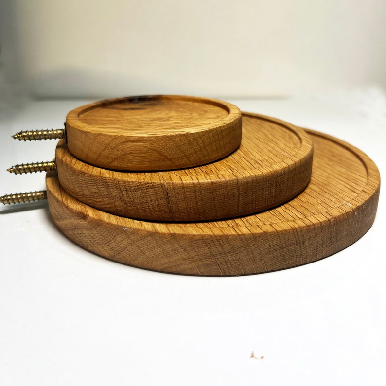 May include: Three round wooden coasters stacked on top of each other. The coasters are made of natural wood and have a smooth finish.