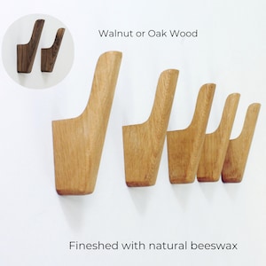 May include: Wooden wall hooks in a light brown finish. The hooks are made of walnut or oak wood and finished with natural beeswax. The image shows five hooks in a row, with two additional hooks in a circle in the upper left corner.