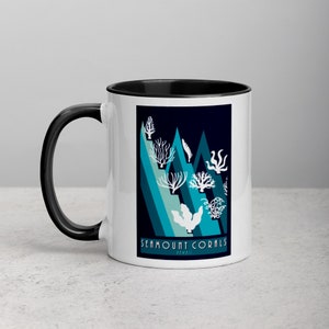 May include: White ceramic coffee mug with a black rim and handle. The mug features a graphic of stylized coral reefs in shades of blue and teal against a dark blue background. The text "Seamount Corals Hawaii" is printed at the bottom of the design.
