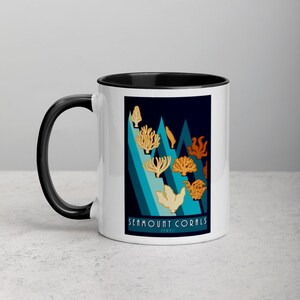 May include: White ceramic mug with a black handle and rim. The mug features a design of coral illustrations in shades of orange and beige against a dark blue background. The text "SEAMOUNT CORALS" is printed at the bottom.