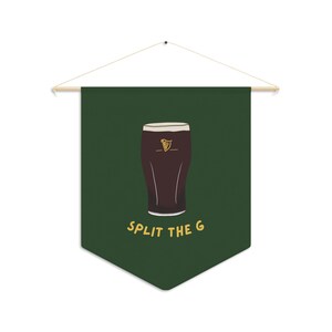 Puede incluir: Pend&oacute;n de tela verde con un vaso de cerveza oscura y el texto "SPLIT THE G" en amarillo.