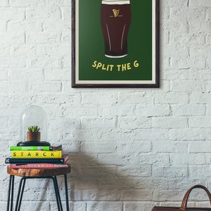 May include: A framed print with a green background and a cartoon illustration of a glass of Guinness beer. The text "SPLIT THE G" is printed in yellow below the glass.