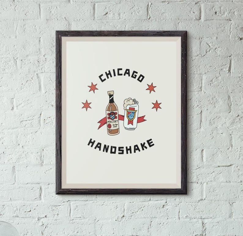 May include: A framed print with a white background and black text that reads "CHICAGO HANDSHAKE". The print features a cartoon illustration of a bottle of Mal&ouml;rt liquor and a can of beer.