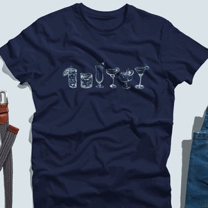 May include: A navy blue t-shirt with a white graphic of different types of cocktails. The graphic includes a margarita, a martini, a daiquiri, a collins, a highball, and a whiskey sour.
