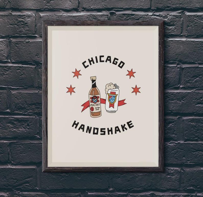May include: A framed print with a white background and black text that reads "CHICAGO HANDSHAKE". The print features a cartoon illustration of a bottle of Mal&ouml;rt liquor and a can of beer with red, white, and blue stars.