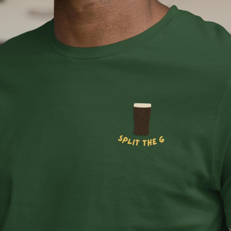 May include: A dark green t-shirt featuring a brown pint of beer graphic and the text "SPLIT THE G" in yellow. The shirt is made of a soft material and has a crew neck.