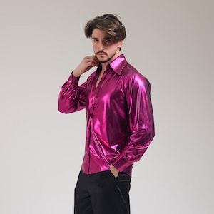 K&ouml;nnte beinhalten: Ein gl&auml;nzendes, fuchsiafarbenes Hemd mit Kn&ouml;pfen und einem breiten Kragen. Das lang&auml;rmlige Hemd hat einen metallischen Glanz und wird mit einer schwarzen Hose kombiniert. Das Hemd scheint aus einem leichten, flie&szlig;enden Material zu sein.
