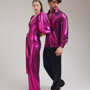 K&ouml;nnte beinhalten: Eine Frau in einem fuchsiafarbenen Overall mit Wickelbund und ein Mann in einem fuchsiafarbenen Hemd mit Kn&ouml;pfen und schwarzer Hose. Die Kleidung hat einen metallischen Glanz, was auf Party- oder formelle Kleidung hindeutet.