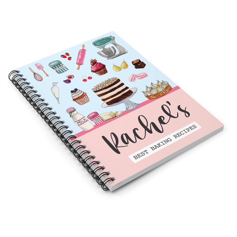 May include: A pink and blue spiral bound notebook with the title "Rachel's Best Baking Recipes" and a watercolor illustration of baking ingredients and desserts.