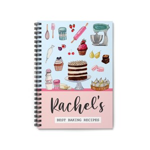 May include: A blue and pink spiral bound notebook with the title "Rachel's Best Baking Recipes". The cover features watercolor illustrations of baking ingredients and desserts, including a cake, cupcakes, cherries, and a rolling pin.