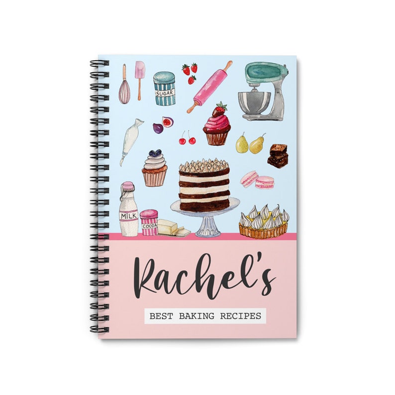 May include: A blue and pink spiral bound notebook with the title "Rachel's Best Baking Recipes". The cover features watercolor illustrations of baking ingredients and desserts, including a cake, cupcakes, cherries, and a rolling pin.