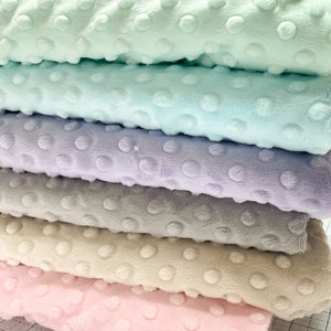 May include: Stack of five fabric squares in different pastel colors. The fabric has a textured, dotted pattern. The colors are light green, light blue, lavender, gray, and light pink.