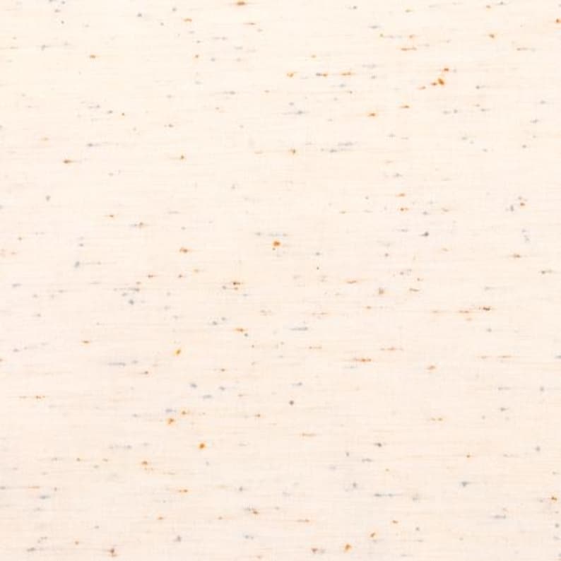 May include: A close-up of a white fabric with a subtle speckled pattern in shades of brown and gray.