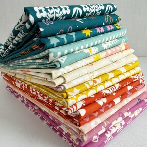May include: A stack of folded fabric in various colors, including teal, yellow, orange, and pink. Each fabric piece features a floral pattern in white, pink, and yellow. The fabrics are neatly arranged, showcasing the different designs and colors.