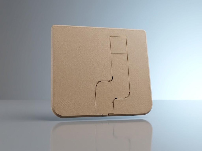 Op de afbeelding: Een vierkante, beige wandplaat met een centraal, verzonken, L-vormig uitgesneden gedeelte. Het oppervlak heeft een fijn gestructureerde afwerking en het ontwerp bevat een kleiner vierkant segment bovenaan het verticale kanaal.